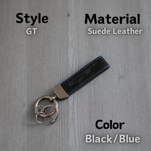 May include: Black and blue suede leather keyring with a silver key ring and the letters "GT" embossed on the leather.