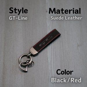 May include: Black suede leather keychain with red stitching and a silver metal ring. The keychain has the text "GT-Line" embossed on it.