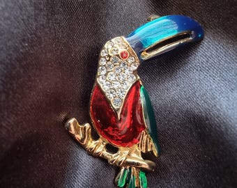 May include: A gold-tone toucan brooch with red, blue, and green enamel and clear rhinestones.