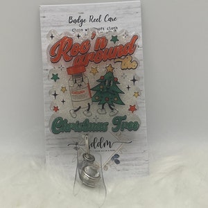 May include: A white card with a red and green Christmas tree design. The card says "Rock 'n around the Christmas Tree" and "Badge Reel Care Clean with a soft cloth".