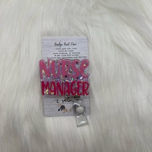 Könnte beinhalten: Rosa-weißer Glitzer-Badge-Rollenhalter mit dem Text "Nurse Manager" und Pflegehinweisen auf der Rückseite.