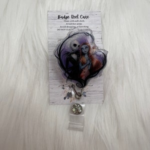 May include: A clear badge reel with a purple and black glitter design featuring Jack Skellington and Sally from The Nightmare Before Christmas. The reel has a silver clip and a white card with the text "Badge Reel Care" and instructions for cleaning and care.