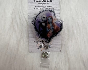 May include: A clear badge reel with a purple and black glitter design featuring Jack Skellington and Sally from The Nightmare Before Christmas. The reel has a silver clip and a white card with the text "Badge Reel Care" and instructions for cleaning and care.