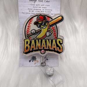 Può includere: Un porta badge con un cartone animato a forma di banana con occhiali da sole e berretto da baseball, che tiene una mazza. La parola "BANANAS" è in lettere arancioni. Il porta badge ha un design trasparente e glitterato con un cordino retrattile.