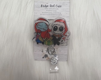May include: A Christmas-themed badge reel featuring Jack Skellington and Sally from The Nightmare Before Christmas. The reel is decorated with glitter and has a clear plastic cover. The text on the card reads "Badge Reel Care", "Clean with soft cloth", "Avoid Hot areas", "Avoid dropping, or knocking", and "DO NOT CLEAN WITH ALCOHOL".