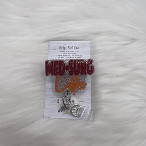 Könnte beinhalten: Ein roter und silberner Badge-Rollenhalter mit dem Text "MED-SURG Life" und einem kleinen silbernen Anhänger. Der Rollenhalter befindet sich auf einem weißen Hintergrund mit einer Karte, auf der "Badge Reel Care" steht und Anweisungen zur Reinigung des Rollenhalters.