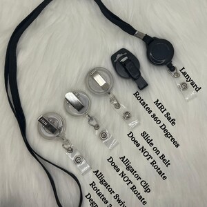 K&ouml;nnte beinhalten: Ein schwarzes Schl&uuml;sselband mit einer einziehbaren Ausweishalterung und einem Krokodilclip. Die Ausweishalterungen sind transparent mit silbernen Metallclips. Text auf dem Bild zeigt, dass sich die Rollen um 360 Grad drehen und MRT-sicher sind.