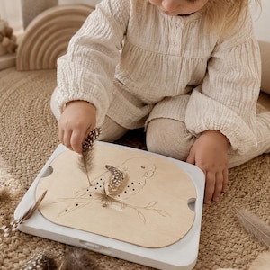 May include: A light beige long-sleeved textured top and matching leggings. A wooden board with a laser-engraved parrot illustration features small holes for inserting decorative brown and white spotted feathers into the bird's wing design.