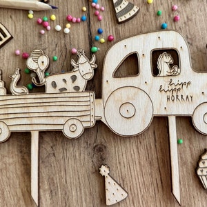 Puede incluir: Topper de pastel de tractor de madera con una vaca, un pato y un caballo adentro. El tractor tiene un letrero que dice "hipp hipp HORRAY".