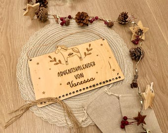 May include: Wooden Advent calendar with a Scandinavian horse design, the text "Adventkalender von Vanessa" is engraved on the sign. The calendar is made of light wood and has a rustic look.
