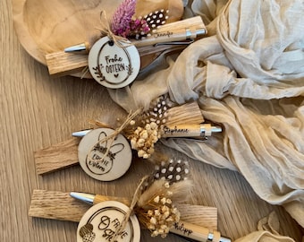 Puede incluir: Tres bolígrafos de madera con nombres personalizados, Jennifer, Stephanie y Philipp, están decorados con flores secas, plumas y etiquetas de madera que dicen "Frohe Ostern" (Feliz Pascua) en alemán.