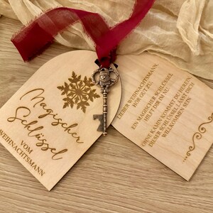 Könnte beinhalten: Zwei Holzanhänger mit einem Schlüssel. Die Anhänger sind mit dem Text "Magischer Schlüssel vom Weihnachtsmann" und "Lieber Weihnachtsmann, hör gut zu. Ein magischer Schlüssel hilft dir im nu. Ohne Kamin kommst du herein, dieser Schlüssel lässt dich willkommen sein..." graviert.
