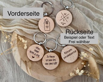 Könnte beinhalten: Vier Holzschlüsselanhänger mit verschiedenen Designs. Die Vorderseite der Schlüsselanhänger zeigt ein Haus, Initialen und einen Familiennamen. Die Rückseite der Schlüsselanhänger ist leer und kann mit Text personalisiert werden.