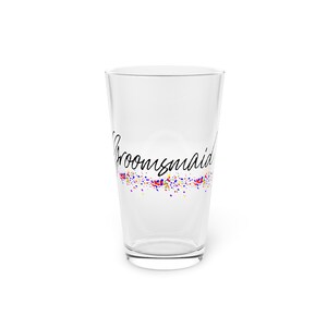 Op de afbeelding: Een helder glas met een zwart-wit ontwerp met de tekst "Broomsmaid" en daaronder een kleurrijk confetti-ontwerp.