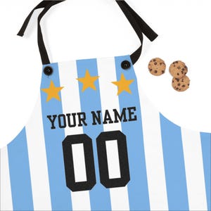 Puede incluir: Un delantal a rayas azules y blancas con tres estrellas amarillas y el texto "YOUR NAME 00".