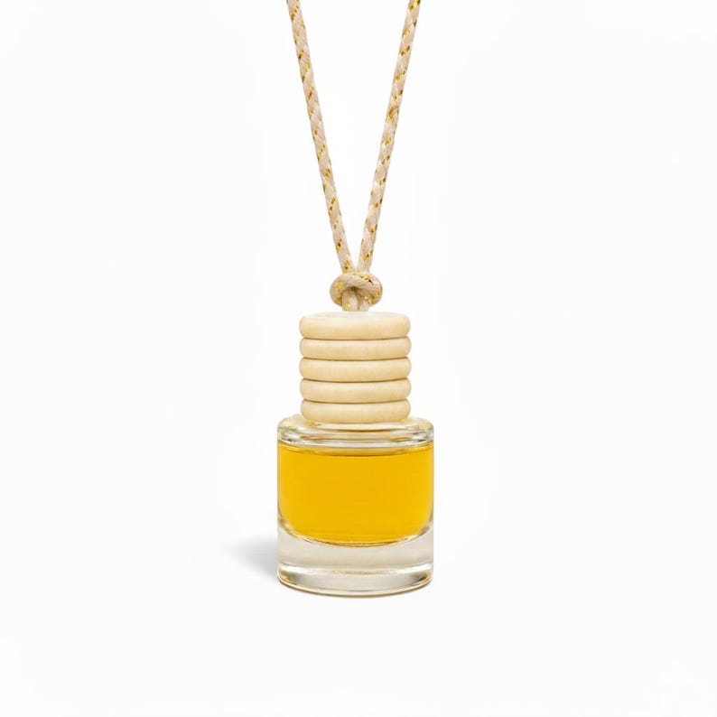 Small glass bottle with yellow liquid and wooden beads on a white background