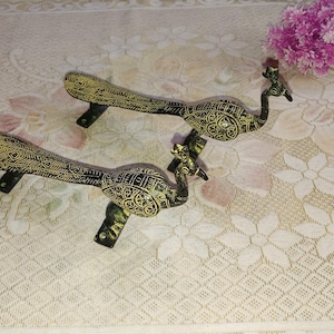 May include: Two ornate peacock-shaped door handles with intricate details. The handles are made of brass and have a gold finish.