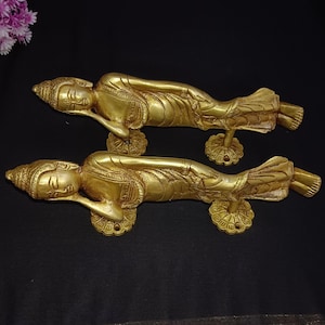 Peut inclure: Une paire de poignées de porte dorées en forme de figures allongées. Les poignées sont ornées de sculptures complexes et présentent un design indien traditionnel.