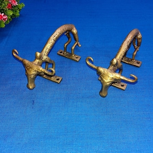 Peut inclure: Deux poignées de porte en laiton en forme de taureau avec un design détaillé. Les poignées sont montées sur une base rectangulaire.