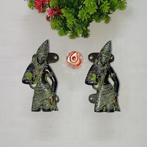 May include: A pair of decorative door handles made of brass with a green patina. Each handle features a detailed figure of a person in a traditional Indian outfit.