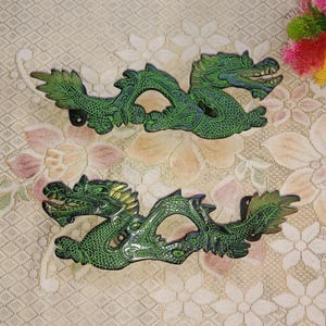 May include: Two green dragon-shaped wall hooks with intricate details. The hooks are made of metal and have a glossy finish.