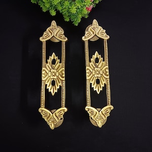 Op de afbeelding: Twee sierlijke messing deurgrepen met een bloemmotief. De grepen zijn rechthoekig met een decoratief boven- en onderstuk.