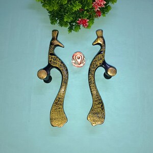 May include: Two peacock-shaped door handles with gold and black accents. The handles are made of metal and have a traditional design.