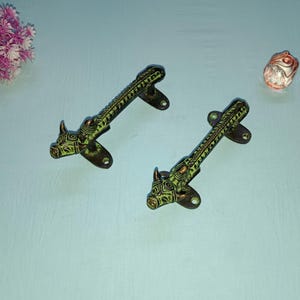 May include: Two ornate green and brown metal door handles with a bull's head design.