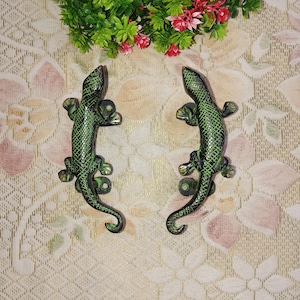 May include: A pair of green metal lizard door handles. The lizards are detailed with scales and have a curled tail.