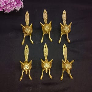 Può includere: Sei batacchio per porte a forma di volpe dorati con un design dettagliato. Ogni batacchio presenta una testa di volpe con una lunga coda appuntita.