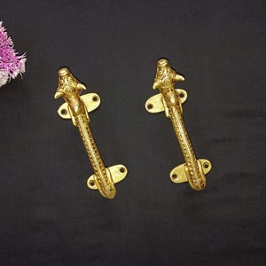 May include: A pair of ornate gold door handles with animal head designs. The handles are made of brass and have a detailed, textured finish.