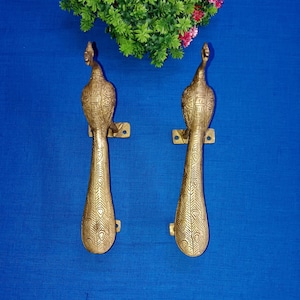 Peut inclure: Une paire de poignées de porte en forme de paon dorées avec des détails complexes. Les poignées sont en laiton et ont un design traditionnel.