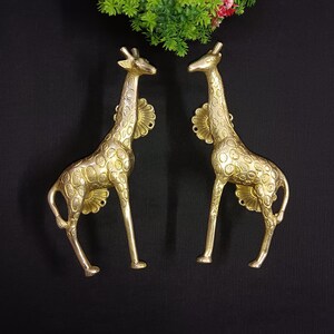 May include: Two gold-colored giraffe door handles with a detailed, textured finish. The giraffes are standing on their hind legs with their necks extended.