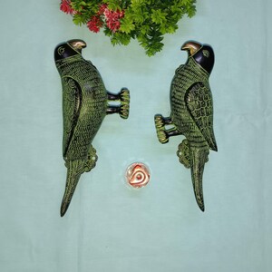May include: Two green and black metal parrot door handles. The parrots are facing each other and have detailed carvings.