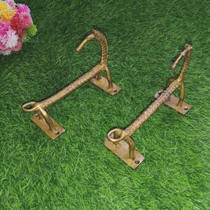 Puede incluir: Dos toalleros de metal dorado en forma de caballos estilizados. Los toalleros están montados sobre una superficie de hierba verde.