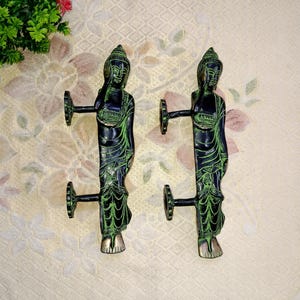 Peut inclure: Une paire de poignées de porte décoratives en laiton avec une patine verte. Chaque poignée présente une figure de Bouddha debout.