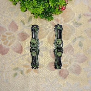May include: A pair of black and green metal door handles with intricate floral designs. The handles are made of brass and have a distressed finish.