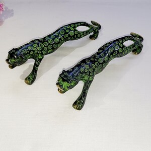 May include: Two black and green leopard-print metal door handles. The handles are in the shape of a leopard crouching and ready to pounce.