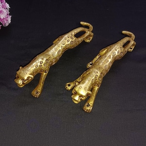May include: Two gold-toned metal leopard door handles. The handles are detailed with a spotted pattern and have a realistic leopard design.