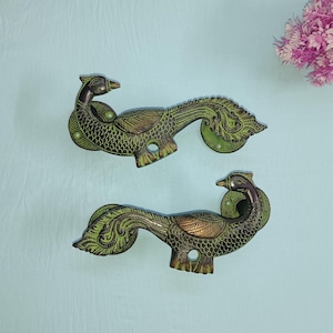 Peut inclure: Une paire de poignées de porte en forme de paon ornées d'accents verts et dorés. Les poignées sont en métal et présentent un design détaillé.