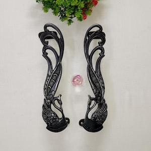 May include: A pair of black metal door handles shaped like peacocks with intricate details. The handles are designed to be used on doors.