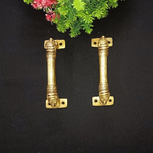 May include: A pair of ornate brass door handles with intricate designs. The handles are a traditional style with a decorative top and a long, slender body.