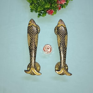 May include: A pair of decorative door handles shaped like fish. The handles are made of brass and have a black and gold finish. The fish have detailed scales and fins.