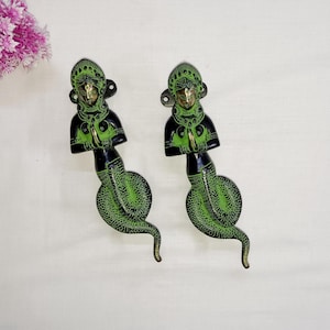 May include: Two decorative door handles made of brass with a green and black finish. Each handle features a woman figure with a snake tail.