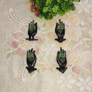 Peut inclure: Quatre poignées de porte décoratives en laiton en forme de main avec des accents verts. Les mains sont dans un geste de donner ou de recevoir.