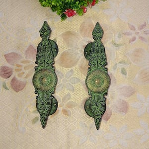 May include: A pair of ornate green and gold door handles with intricate floral designs. The handles are made of metal and have a traditional style.