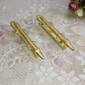 May include: Two gold-toned alligator-shaped door handles with detailed scales and a textured finish.