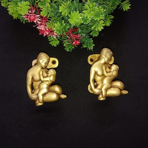 Puede incluir: Un par de tiradores de puerta de metal dorado, cada uno representando una figura de madre e hijo. Los tiradores son detallados y tienen un estilo tradicional.