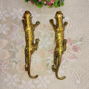 Può includere: Due maniglie per porte in metallo dorato a forma di leopardo con un motivo a macchie. Le maniglie hanno la forma di un leopardo che arrampica su un muro.