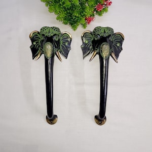 May include: A pair of black and green elephant head door handles with intricate details. The handles are made of brass and have a traditional Indian design.